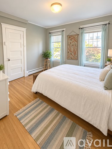 A bedroom with a large bed and a wooden floor.