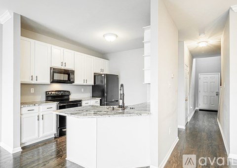 A kitchen with white cabinets and a black refrigerator.