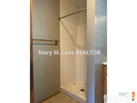 A shower with a glass door and a metal grab bar.