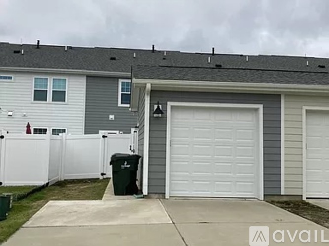 A house with a grey garage door and a white fence.