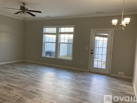 A spacious room with a ceiling fan and a chandelier.