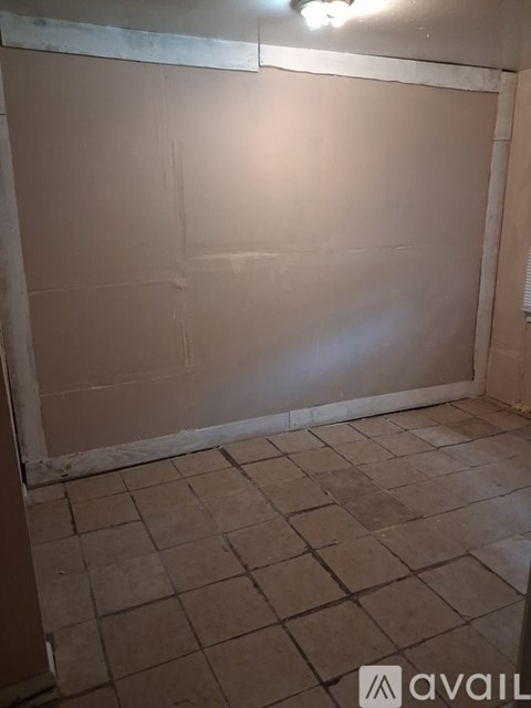 A room with a tiled floor and a wall covered in drywall.
