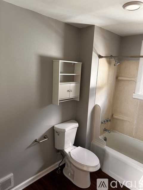 A white toilet with a cabinet above it in a bathroom.