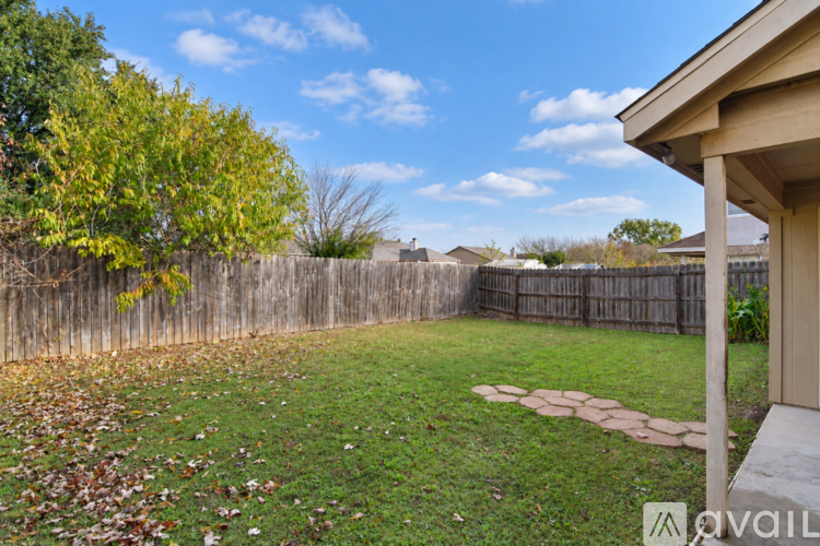 A backyard with a wooden fence and a grassy area.
