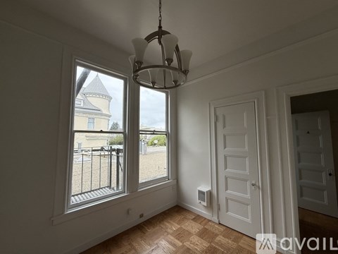 A room with a large window overlooking a patio with a chandelier hanging from the ceiling.