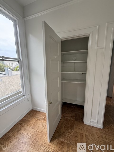 A white door is open to a room with a wooden floor.