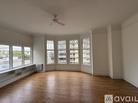 A spacious room with wooden floors and large windows.