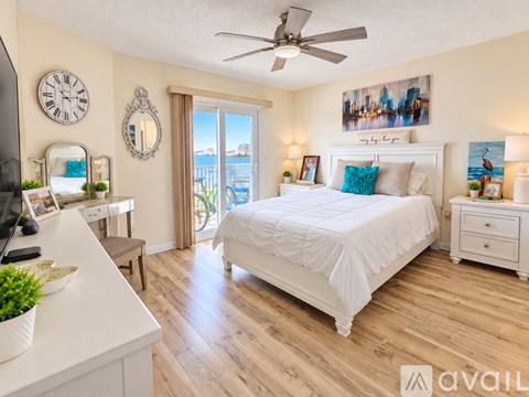 A bedroom with a large bed, a ceiling fan, and a view of the city through the window.