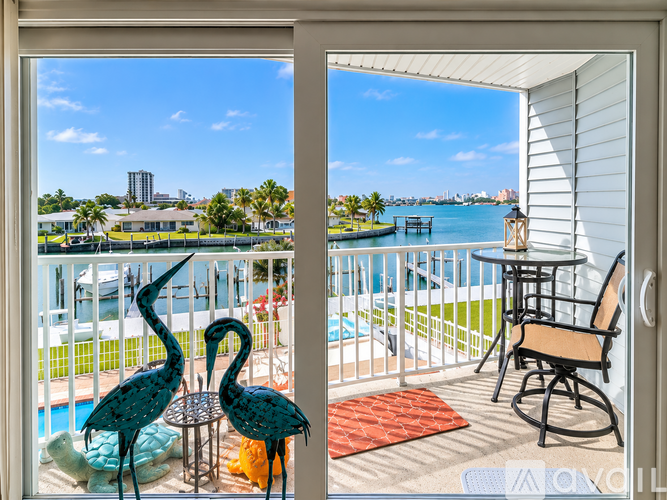 A balcony with a table and chairs overlooking a body of water.