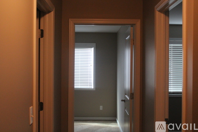 A hallway with a door on the left and a window with blinds on the right.