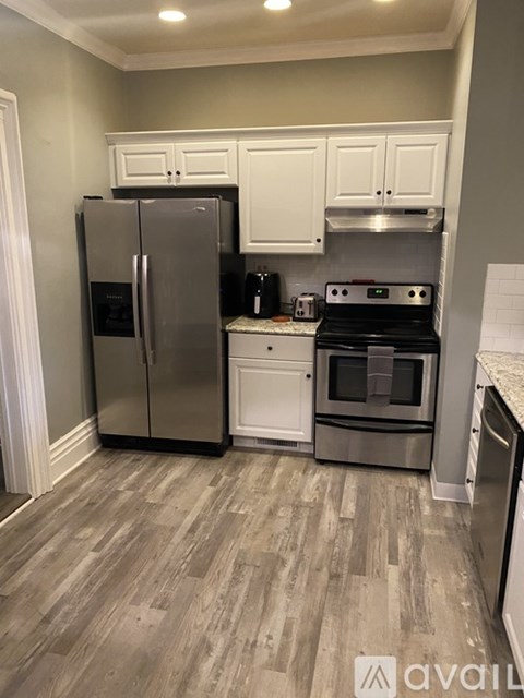 A kitchen with a stainless steel refrigerator and oven, and white cabinets.