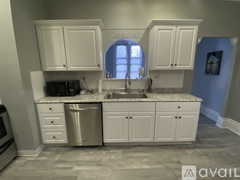 A kitchen with white cabinets and a marble countertop.