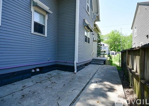 A grey house with a concrete walkway in front.