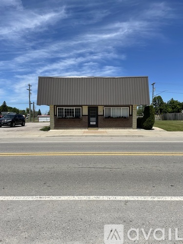 A building with a grey roof and a black door is situated on a street.