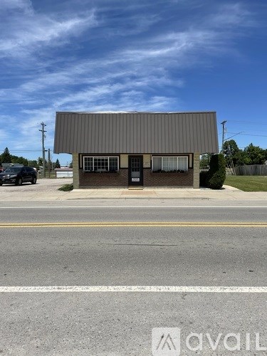 A building with a grey roof and a black door is situated on a street.