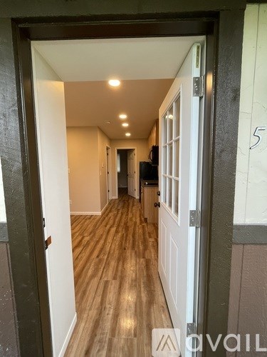 A hallway with wooden floors and white walls.