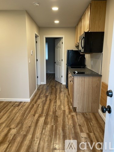 A kitchen with wooden floors and a black microwave above the stove.