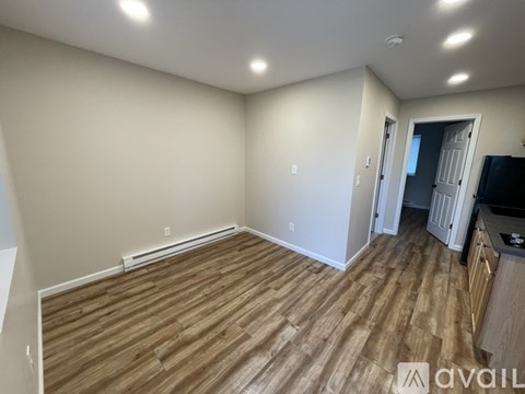 A room with wooden flooring and a wall-mounted television.