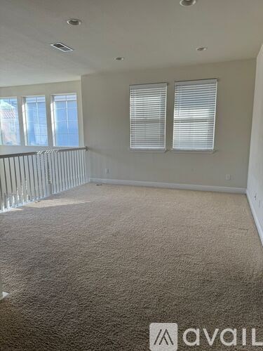 A carpeted room with a window and a railing.