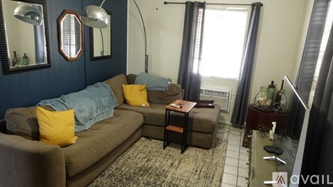A living room with a brown couch and a rug.