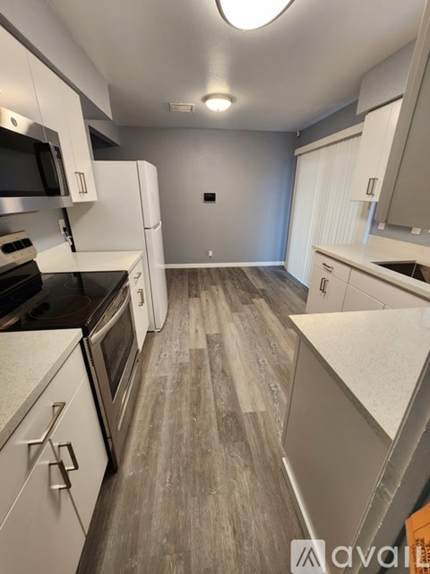 A kitchen with white cabinets and a grey floor.