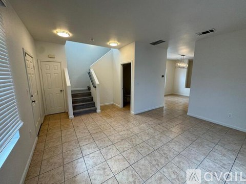 A spacious room with a staircase and a chandelier.