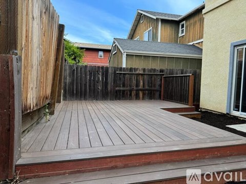 A wooden deck leads to a fenced backyard.