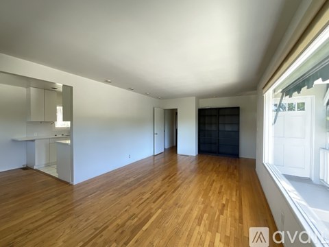 A spacious room with wooden flooring and white walls.