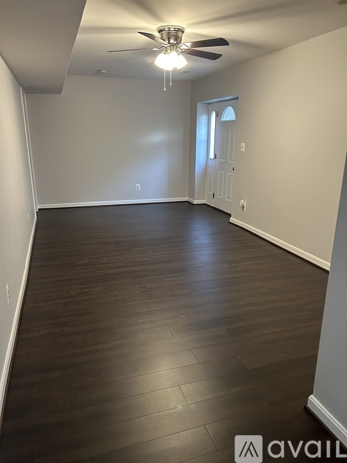 A room with a ceiling fan and wooden flooring.