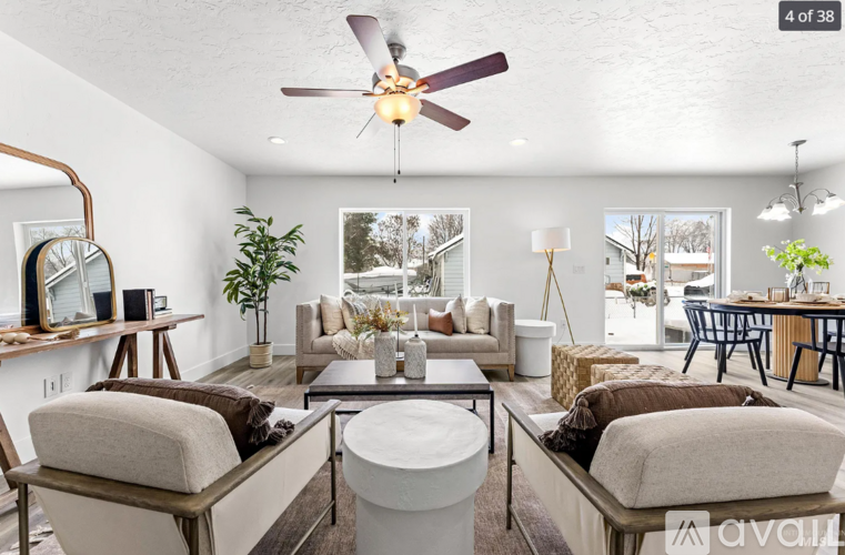 A living room with a white ceiling fan and a large mirror on the wall.
