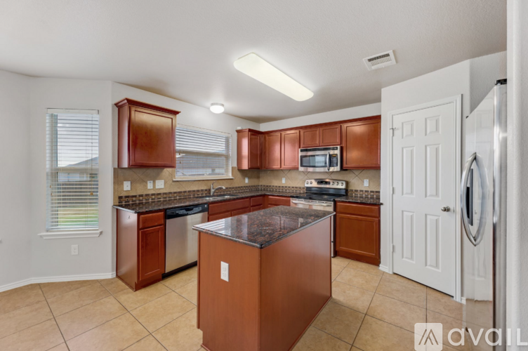 A kitchen with brown cabinets and a black countertop.