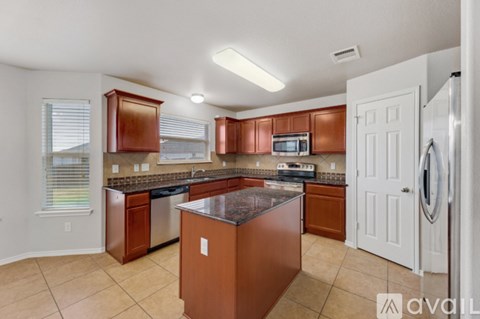 A kitchen with brown cabinets and a black countertop.