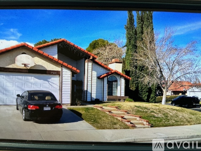 A black car is parked in front of a house with a garage.