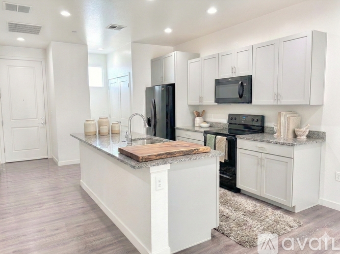 A kitchen with white cabinets and a black refrigerator.