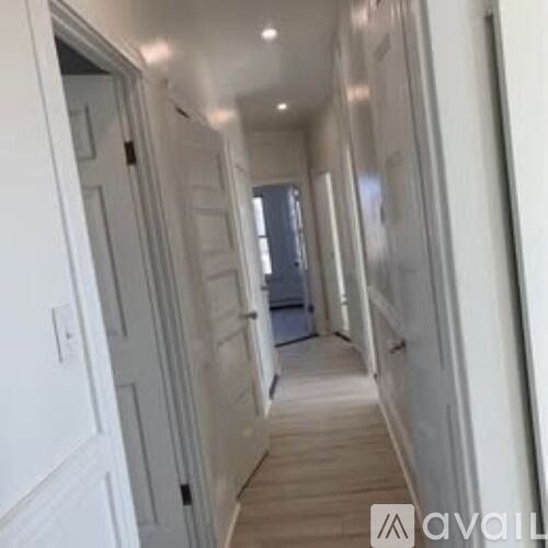 A long hallway with white walls and wood flooring.