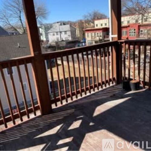 A wooden deck with a railing and a view of a residential area.