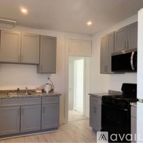 A kitchen with a black oven and grey cabinets.
