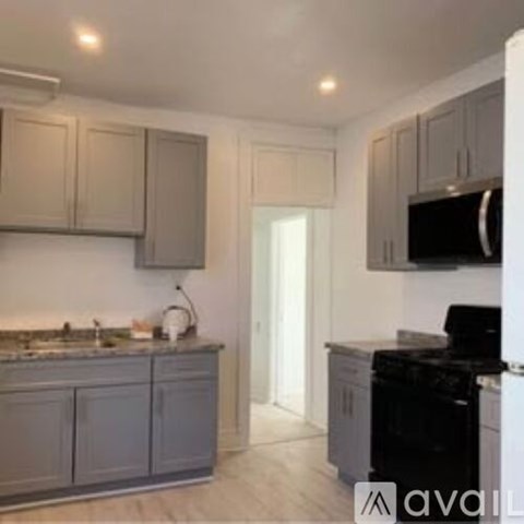 A kitchen with a black oven and grey cabinets.