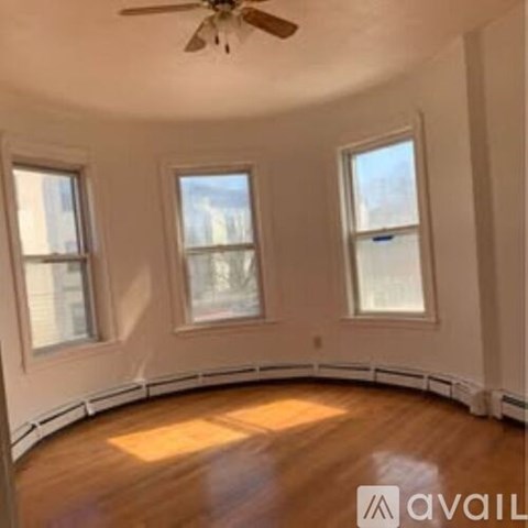 A room with a ceiling fan and three windows.