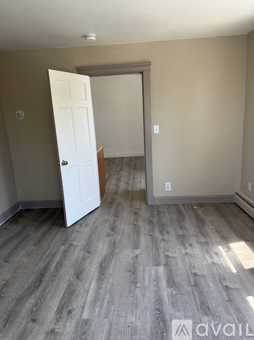A room with a white door and a grey floor.