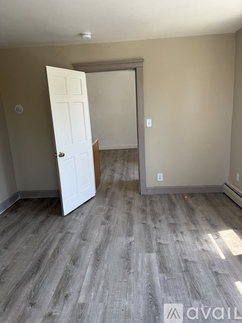 A room with a white door and a grey floor.