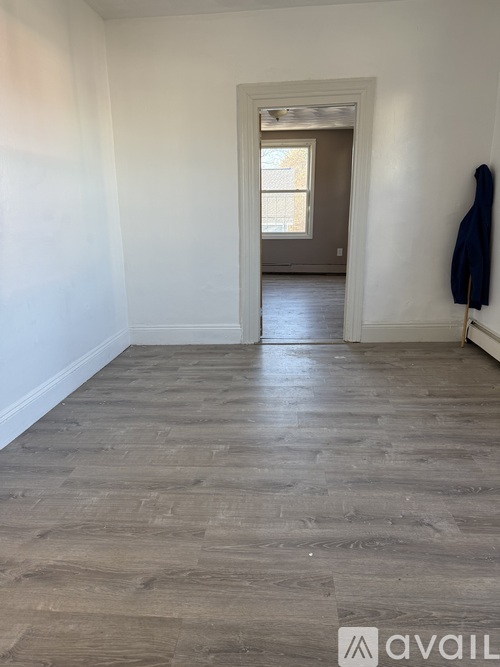 A room with wooden flooring and a coat hanging on a hook.