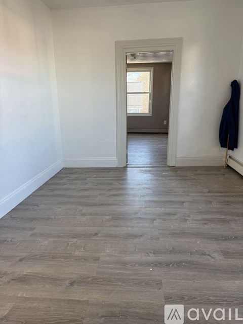A room with wooden flooring and a coat hanging on a hook.