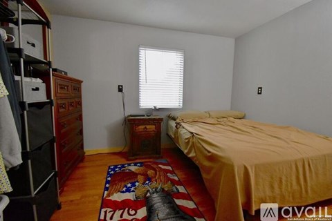 A bedroom with a bed, a dresser, and a window with blinds.