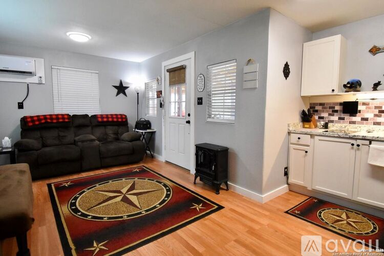 A living room with a black couch and a rug with a star design.