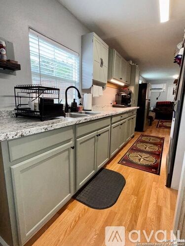 A kitchen with wooden floors and white cabinets.