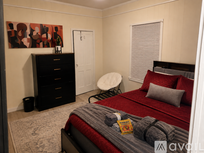 A bedroom with a bed, chair, and a painting on the wall.