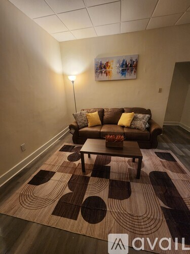 A living room with a brown couch and a patterned rug.