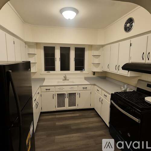 A kitchen with white cabinets and black appliances.