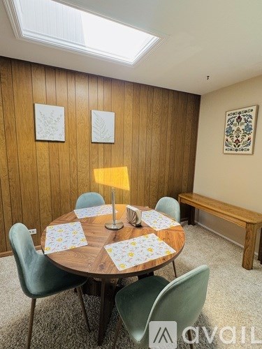 A dining room with a round table surrounded by chairs and a bench.